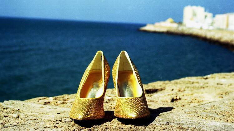 Pair of gold stilettos placed in front of an ocean view 