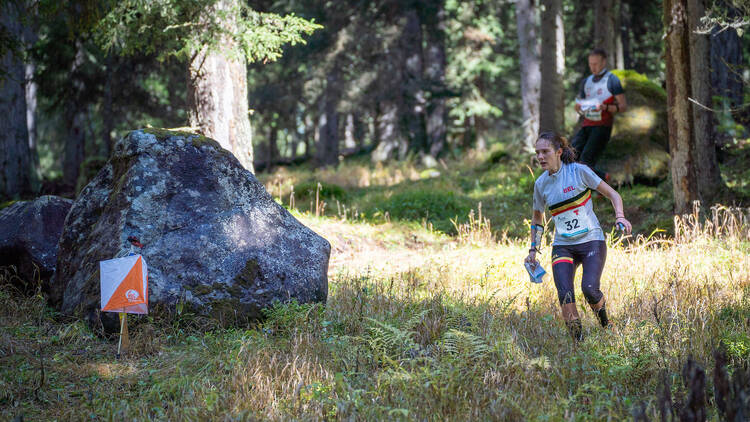 A woman runs through a forest to reach a checkpoint