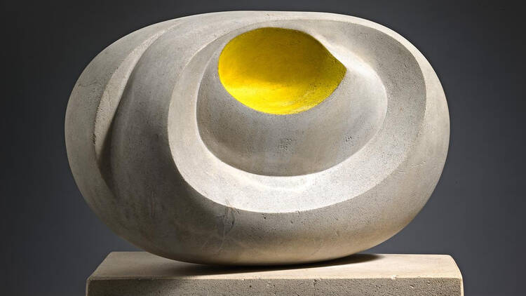 arbara Hepworth, Eidos, 1947, an orb-like sculpture made of chalky grey stone, with a central section painted yellow