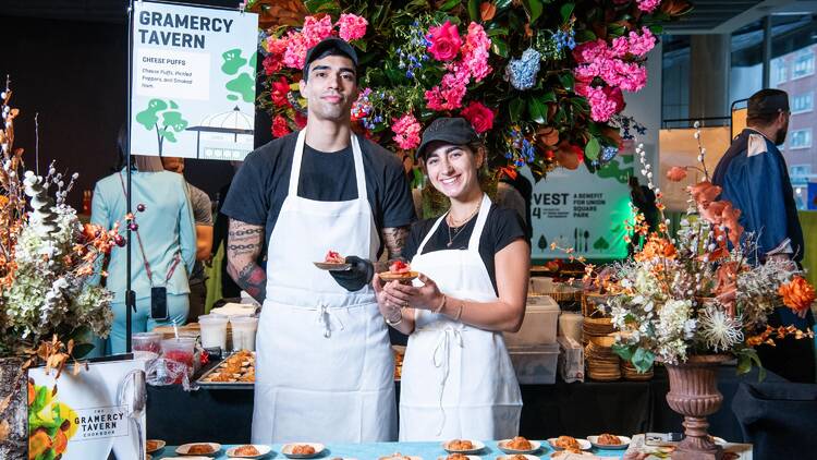 Two chefs hold up tasting plates.
