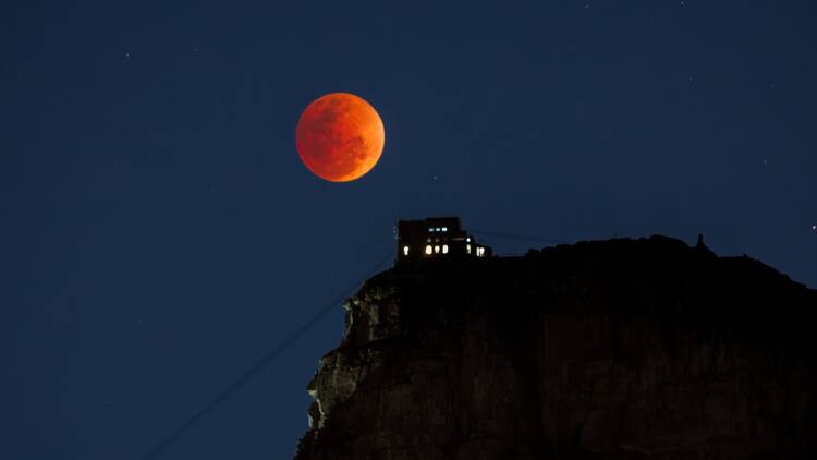  The Blood Moon peaking just above Table Mountain Aerial Cableway. 