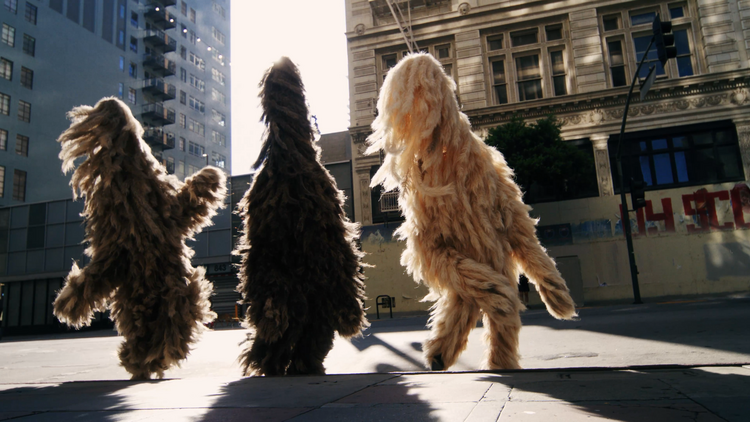 Large faceless hairy costumed figures from The Cortège.