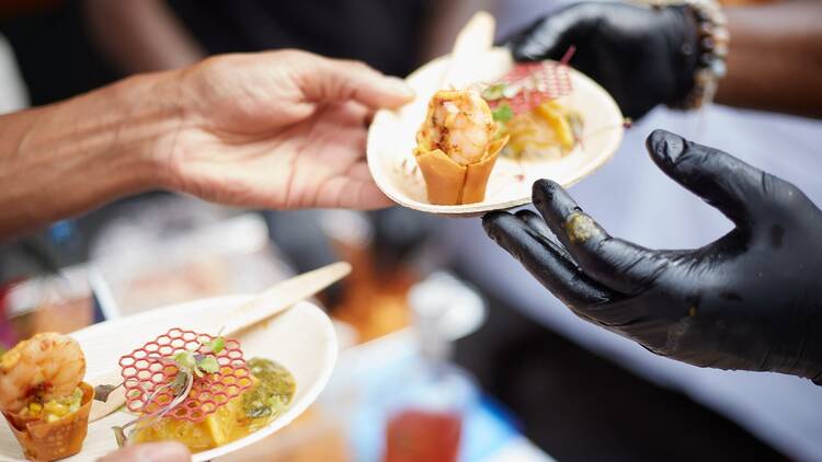 Two hands exchanging small plates of food