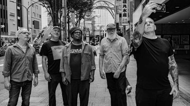 The members of Tortoise are pictured standing in the middle of a street. The members of Tortoise are pictured standing in the middle of a street.
