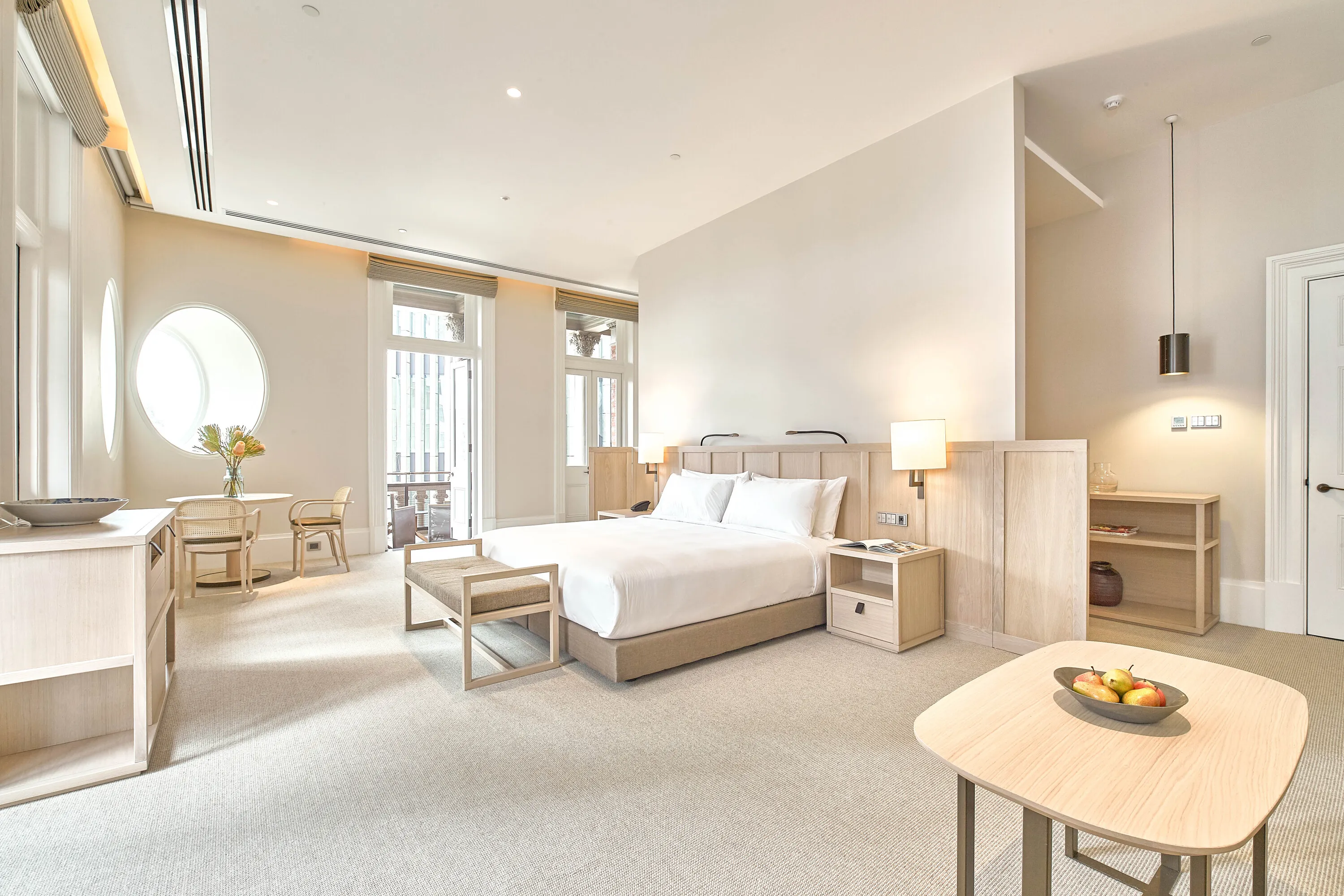 White hotel room with bed and tables
