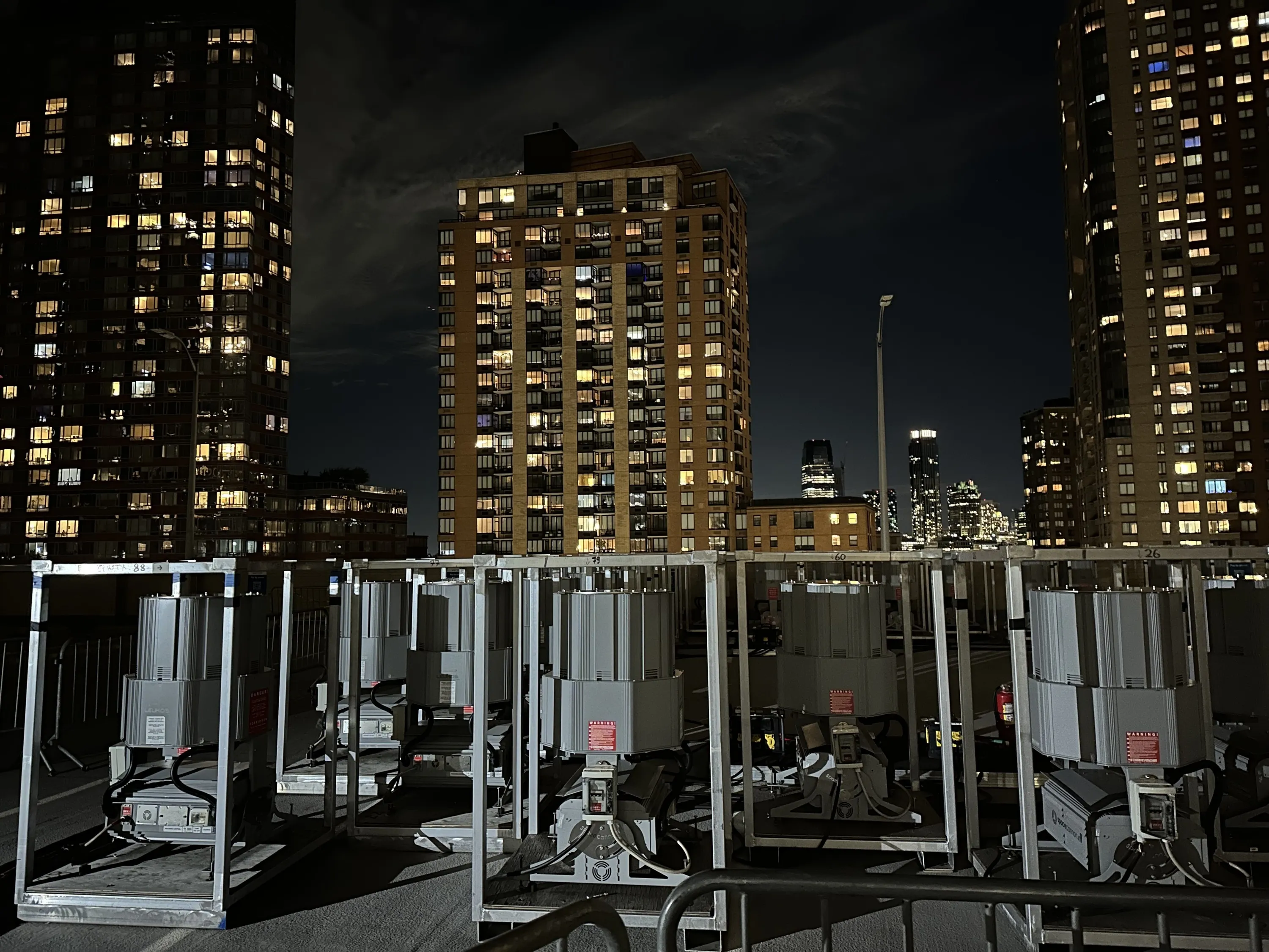 A large array of spotlights on the rooftop of a parking garage with buildings in the background.