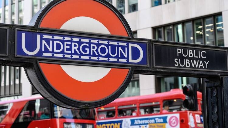 London Underground sign with buses in the background