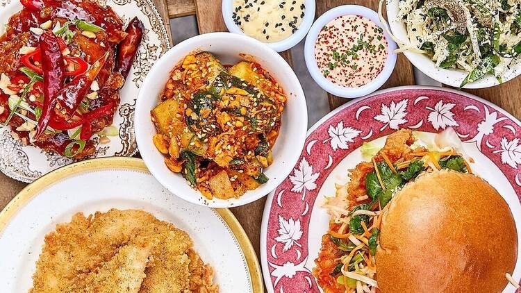 Table full of fried chicken, burgers and smashed cucumber 