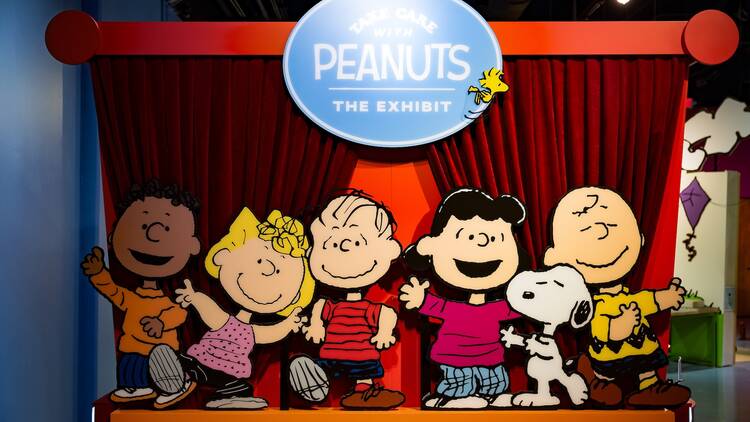 Painted cutouts of Peanuts characters greet visitors of the 'Take Care with Peanuts' exhibit.