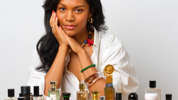 A woman sitting in front of a collection of perfume bottles