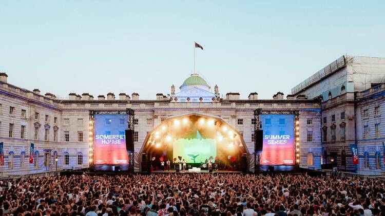 Wide shot of crowds in front of a stage in the courtyard of Somerset House at dusk