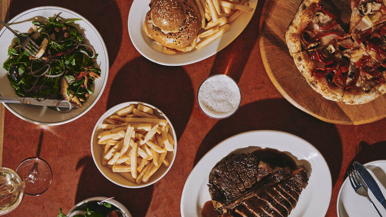 Flat lay of plates of food like steak and pizza