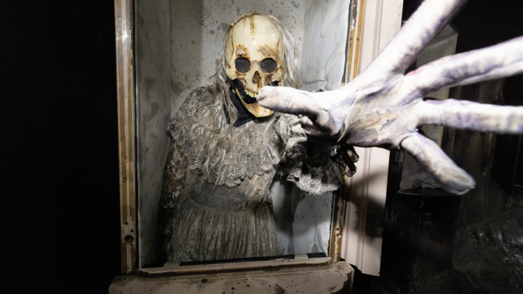 An undead poltergeist reaches out from a coffin in Horror Nights' Poltergeist maze.