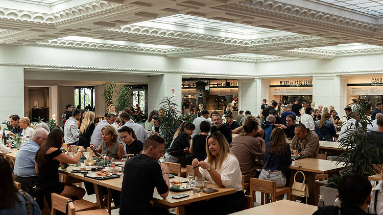 Emberek asztalnál és széken esznek a Time Out Market Budapesten a Corvin Palace-ban