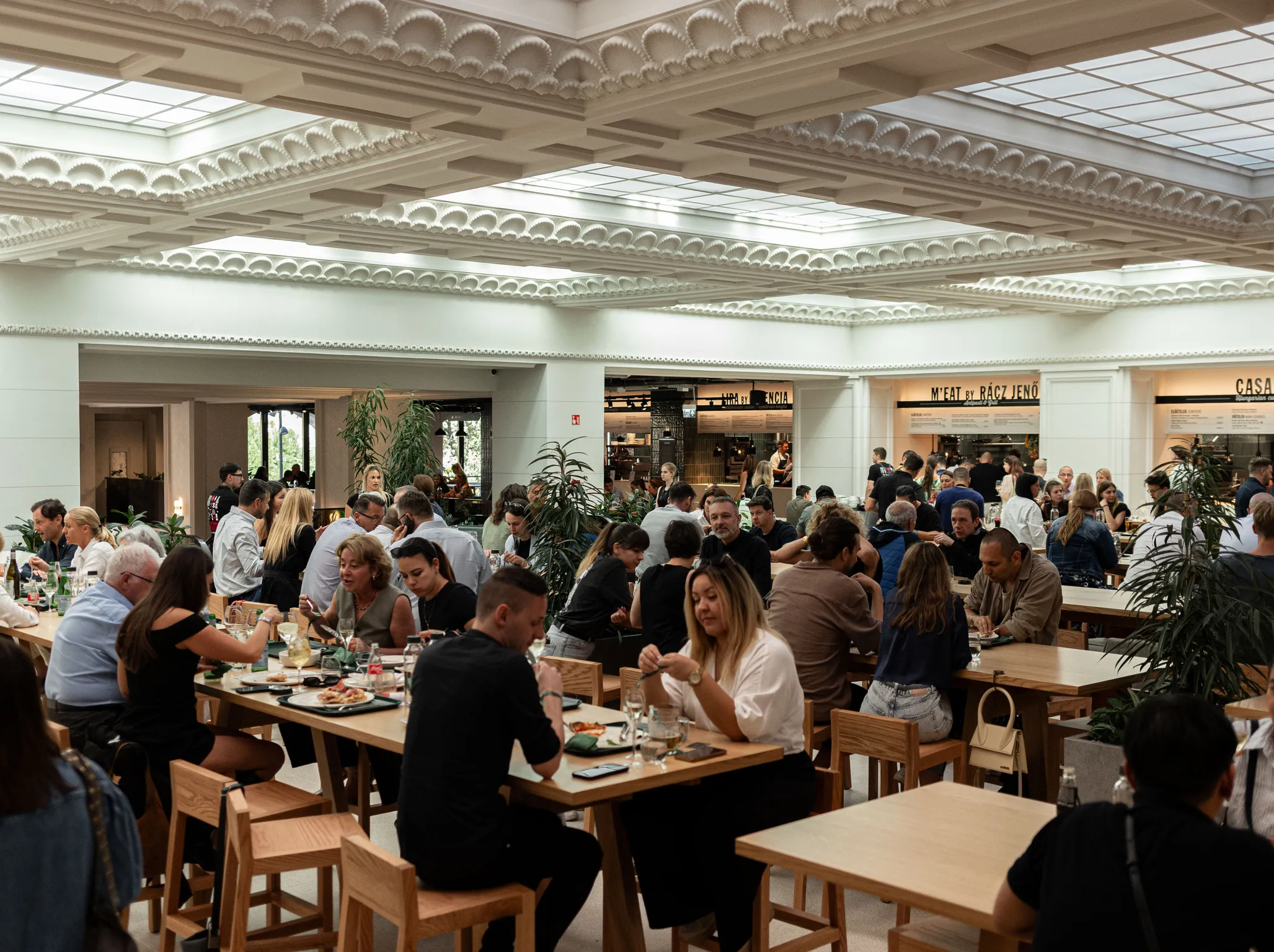 Emberek asztalnál és széken esznek a Time Out Market Budapesten a Corvin Palace-ban