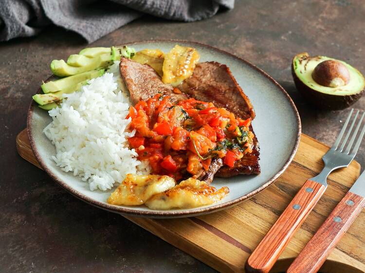 colombian food. flanksteak or Sobrebarriga en salsa criolla  -  colombian dish traditional - beef steak with tomatoes sauce, rice, avocado, bananas fries                                  