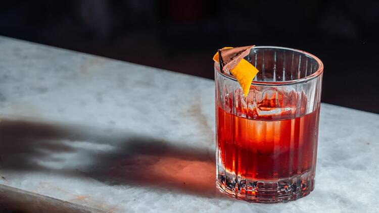 Coffee Negroni (R$ 46), feito com Campari, vermute tinto e gin infusionado em café, acompanhado de chocolate com avelã e laranja