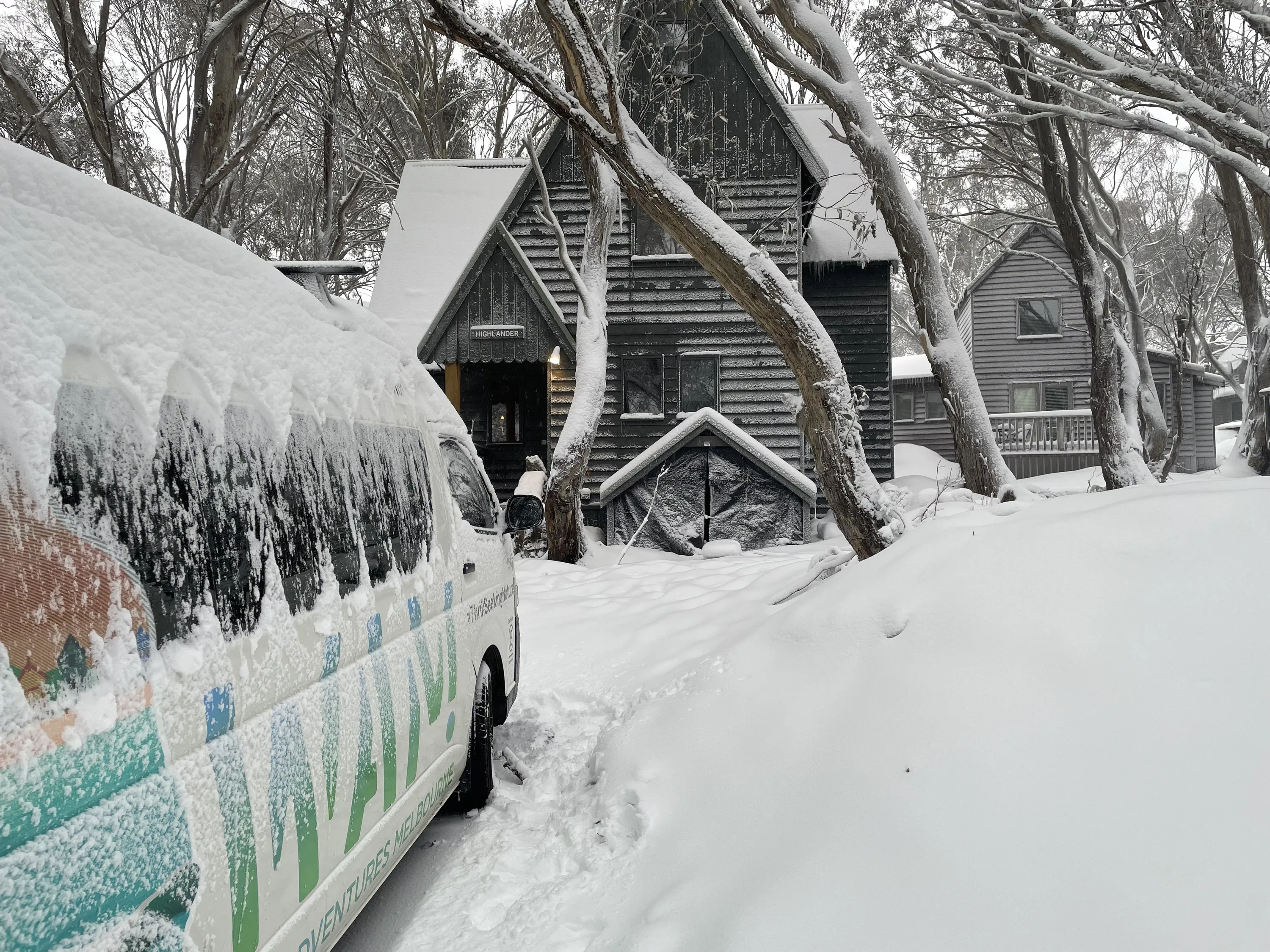 A snow-covered van outside a chalet.