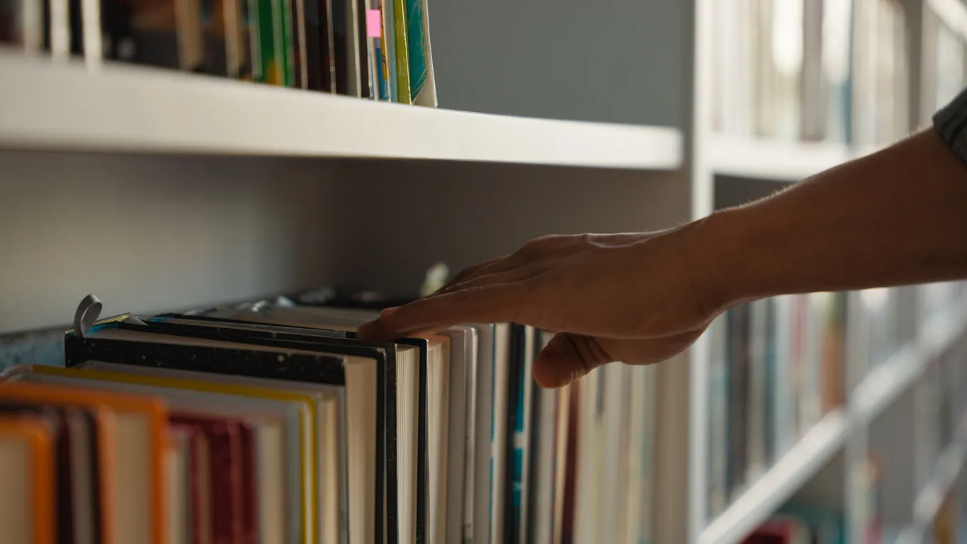A man reaching for book on shelf