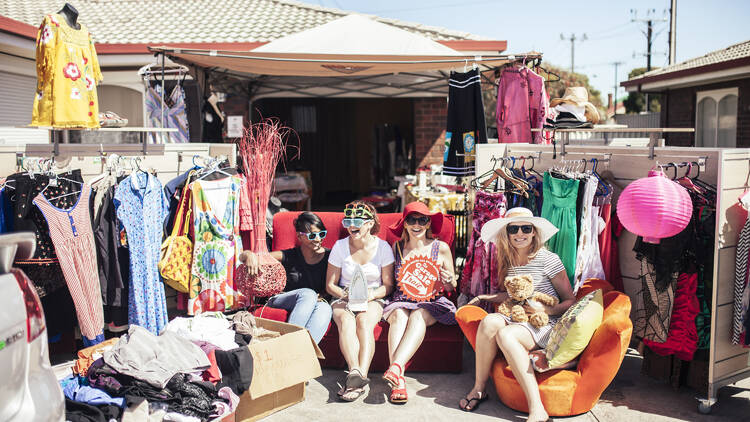 People sitting on a couch outside at a garage sale.