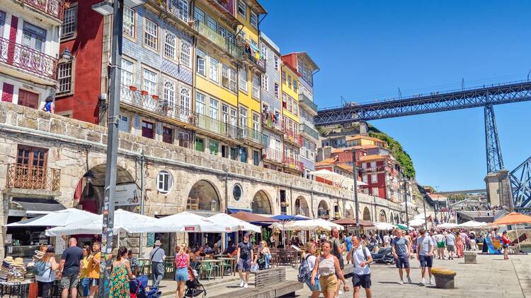 People walking at the Ribeira neighborhood. Ribeira's narrow cobblestone streets are dotted with small bars and restaurants serving classic Portuguese cuisine. People walking at the Ribeira neighborhood. Ribeira's narrow cobblestone streets are dotted with small bars and restaurants serving classic Portuguese cuisine.