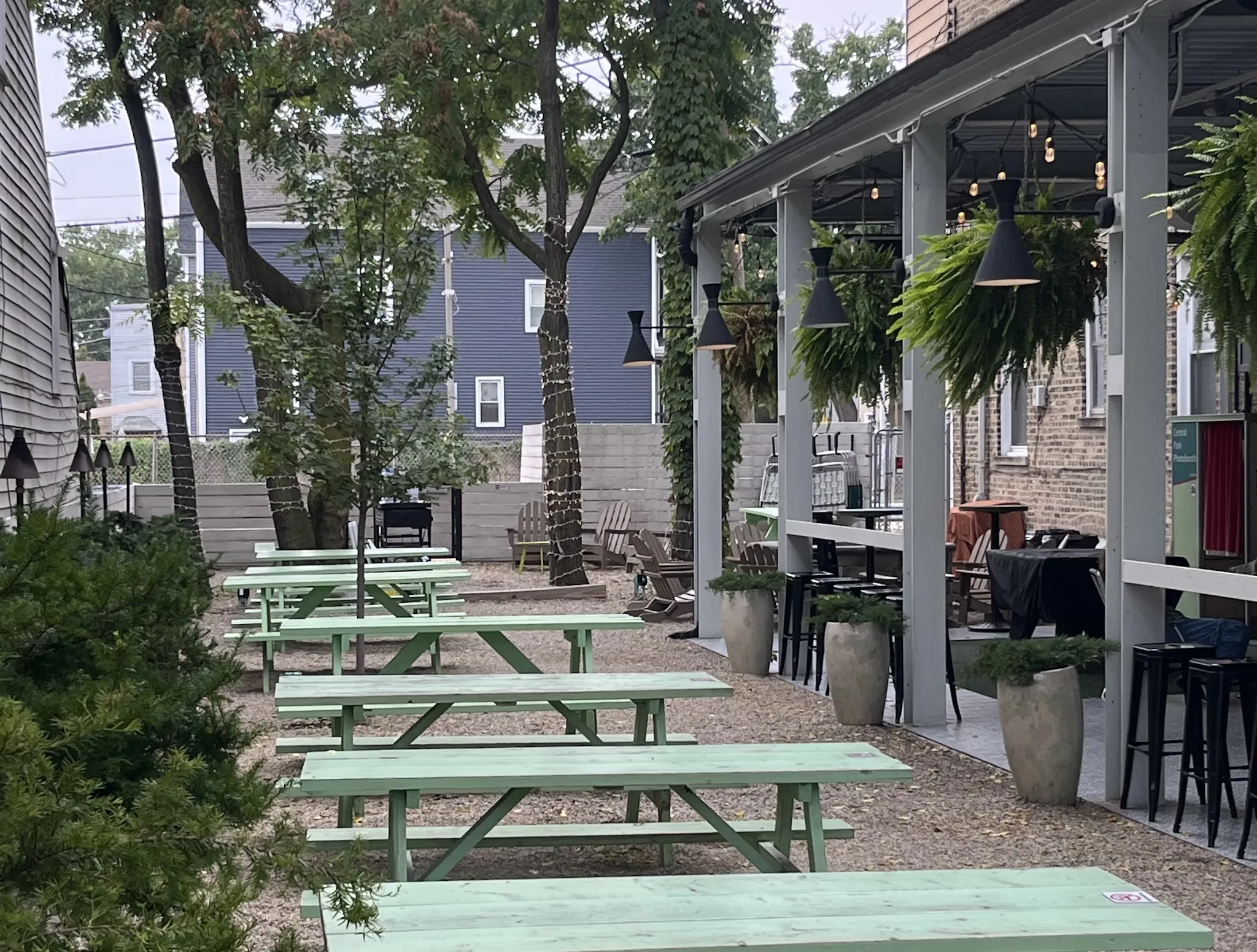 The outdoor patio at Central Park Bar, adorned with. hanging ferns, tea picnic tables and string lights.