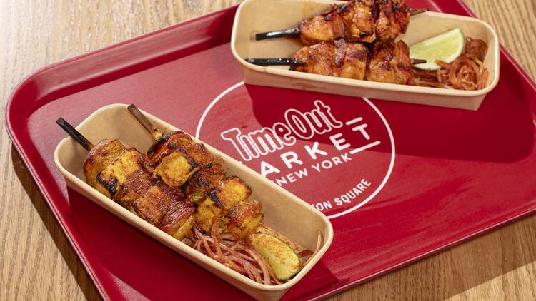 Two kebabs on a red tray that reads Time Out