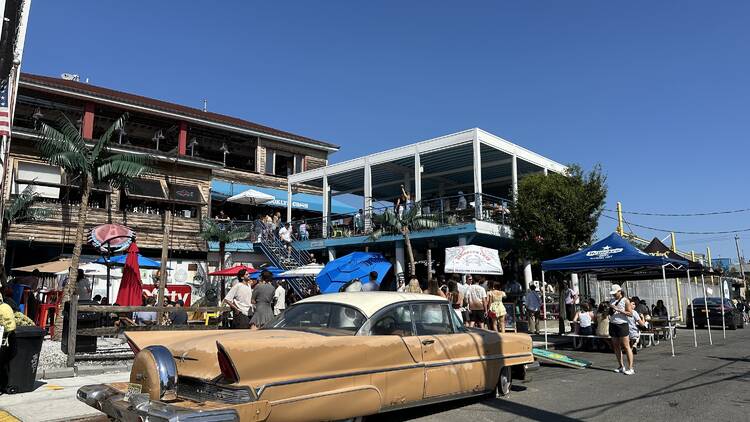 A vintage car sits outside of a restaurant in Red Hook on a sunny day.