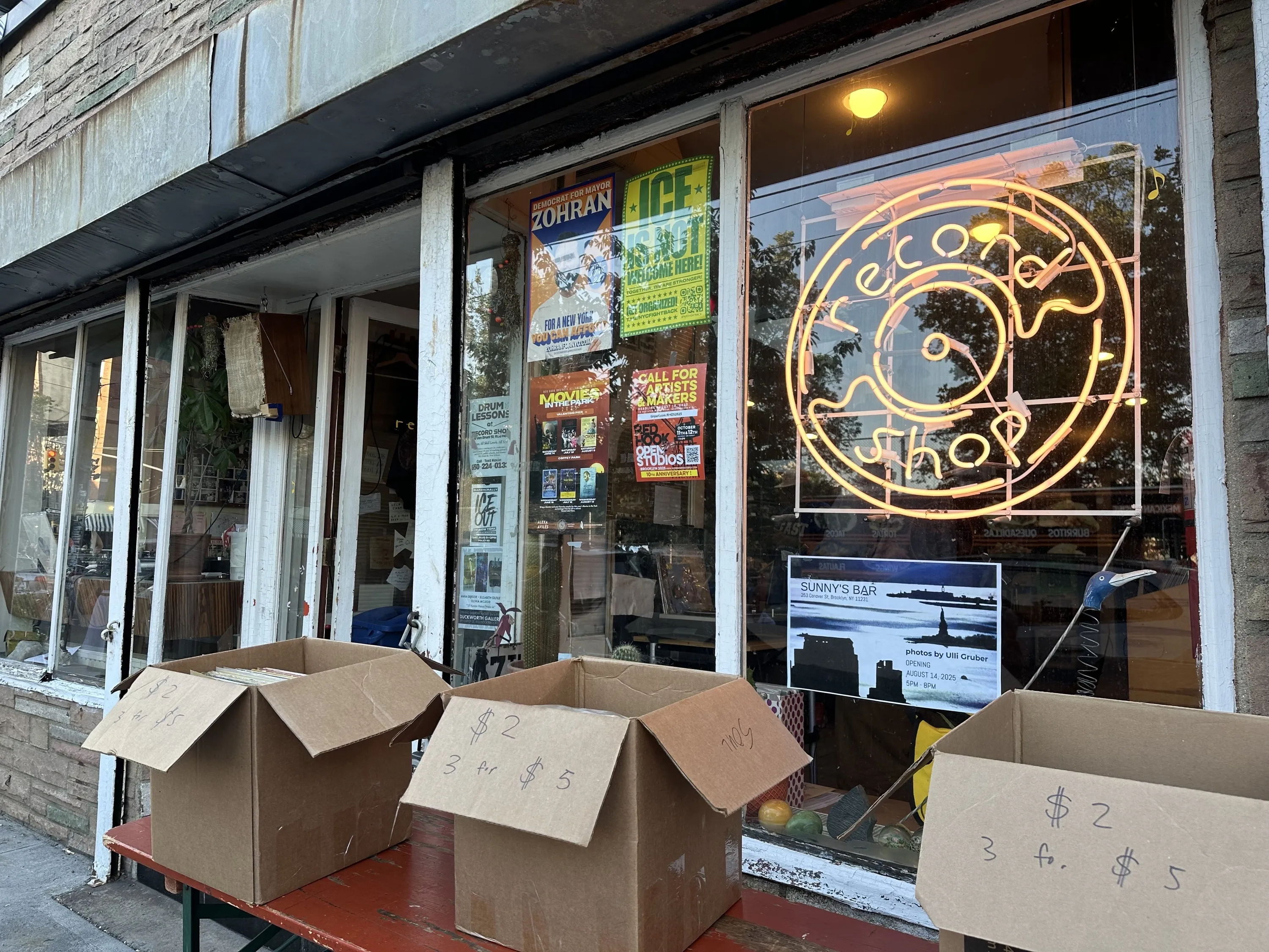 Several boxes of records sit outside of a record store.