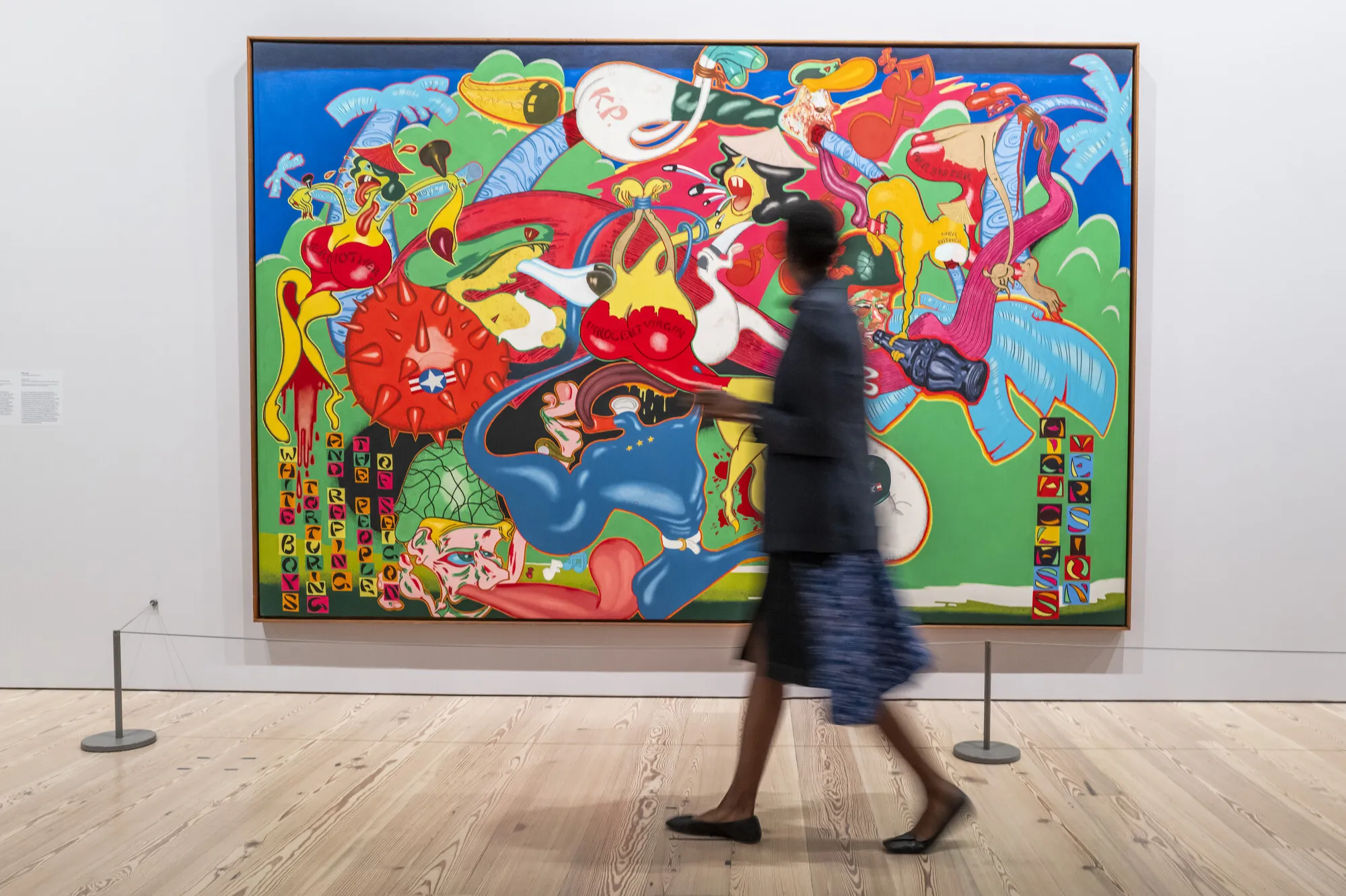 A person walks by a colorful painting on a wall.