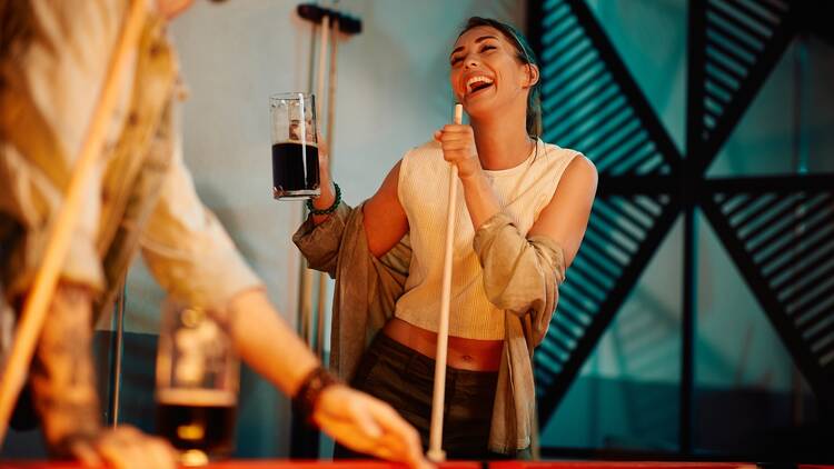 Woman drinking beer at pool hall