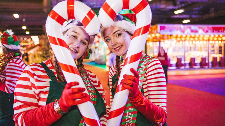 Two women holding large candy canes at Winter Funland.