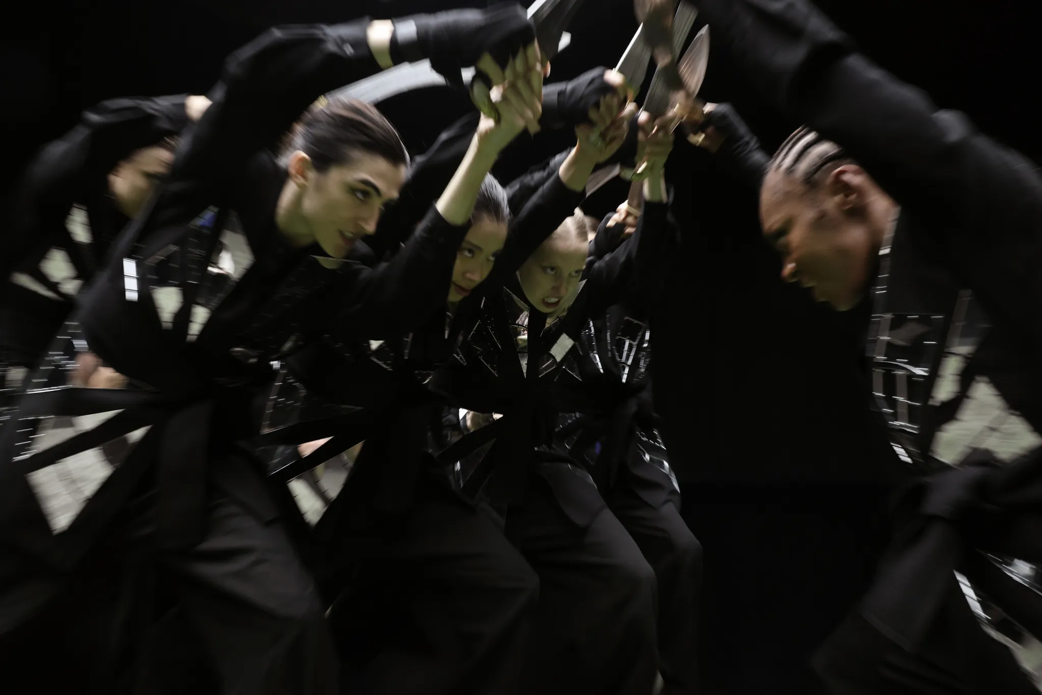 Performers dressed in black clashing their swords together