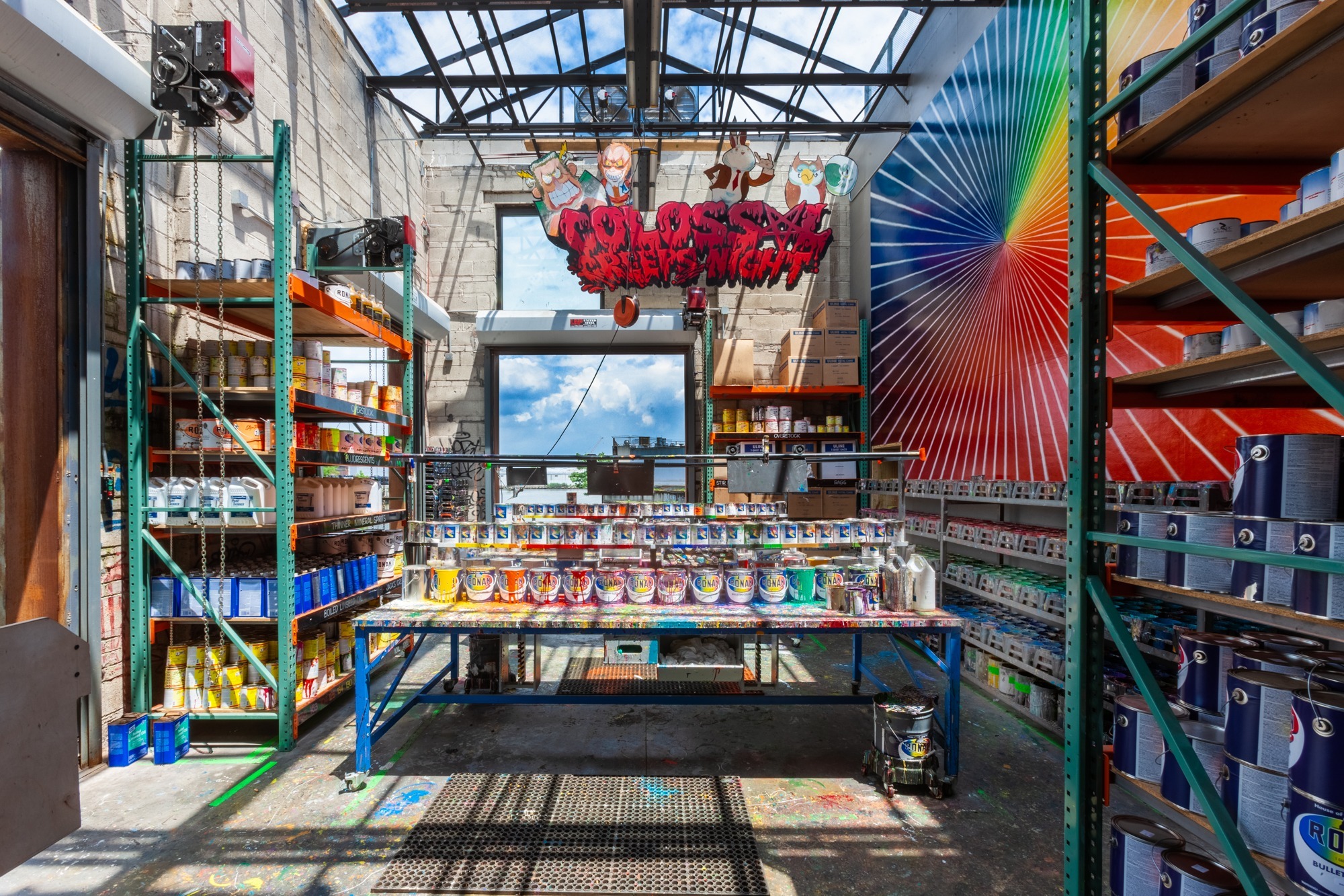 Rows of spray paint sit inside a sun-drenched studio.
