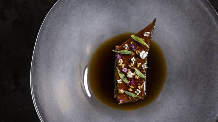 A dish from Atomix on a silver plate with flowers and herbs
