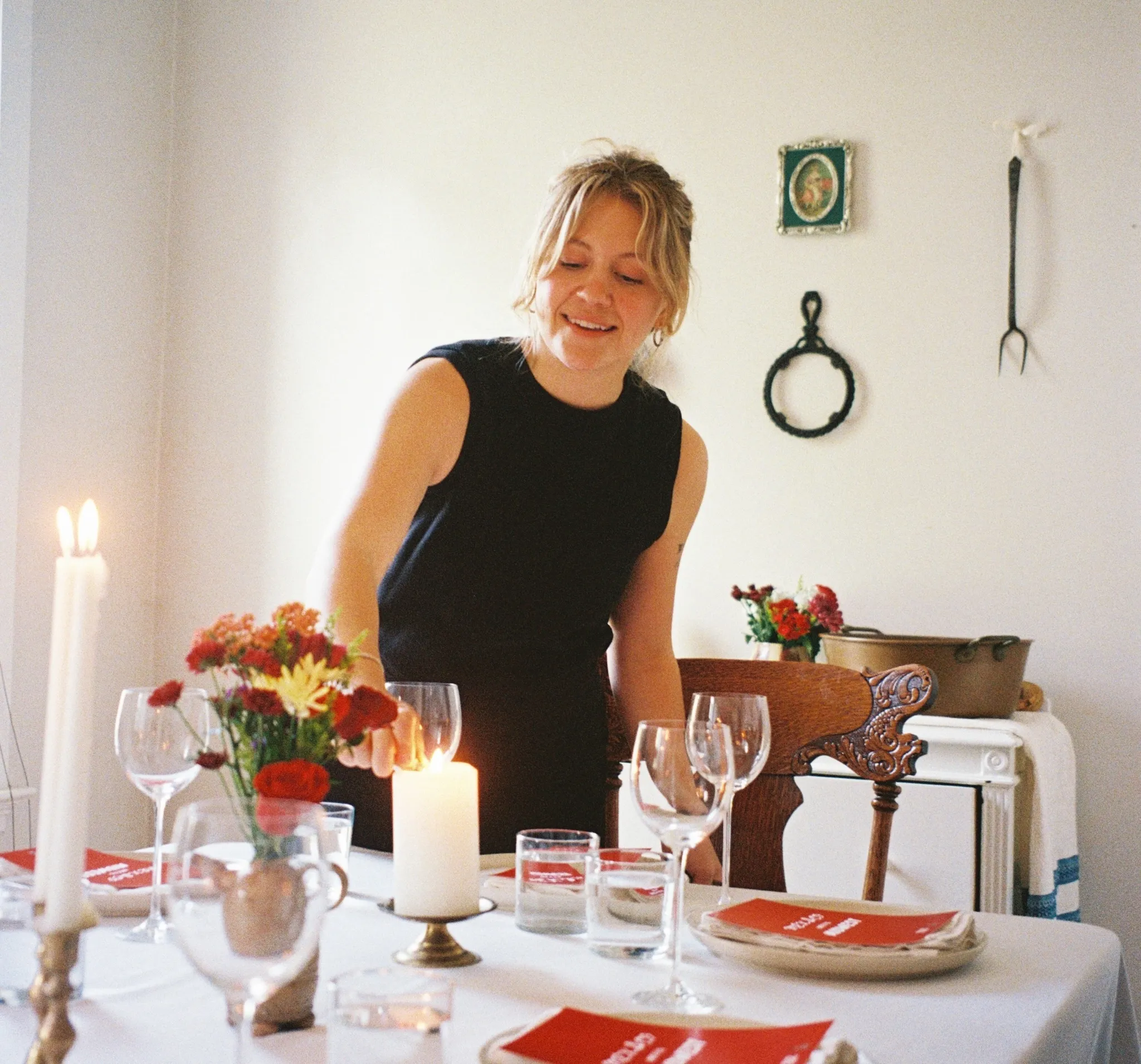 Brook Anderson, founder of Second Helping Supper Club, lights a candle at a communal dinner table.