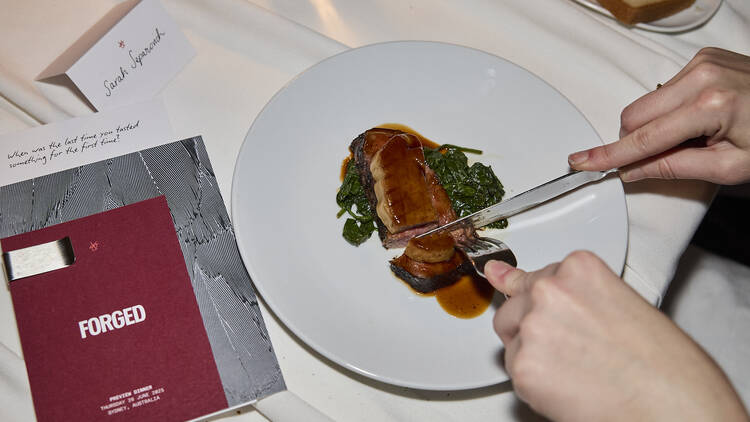 Person cutting into meat on white plate