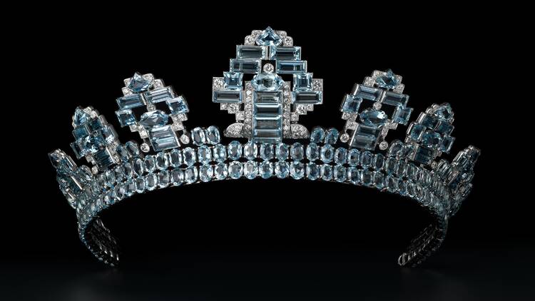 A diamond and aquamarine tiara against a black backdrop.