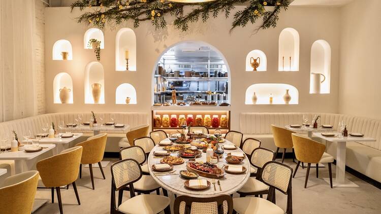 Motek Motek's interior with white walls, yellow chairs and a view inside the kitchen