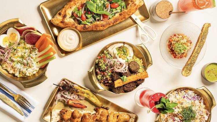 A dtable full of dips, rice and chicken kebabs