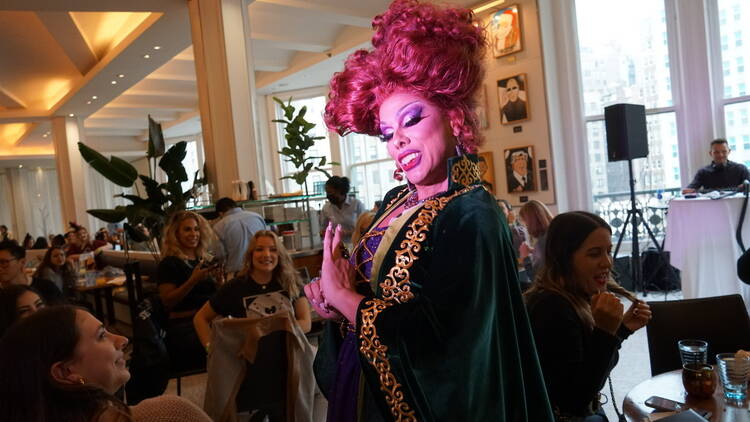 a drag queen in a halloween costume performing during a drag brunch 