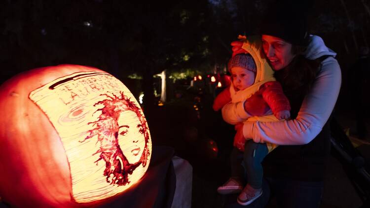 A parent and child admire a jack-o'-lantern at the Chicago Botanic Garden.