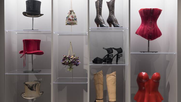 A collection of top hats, boots and bustiers at a museum exhibit.
