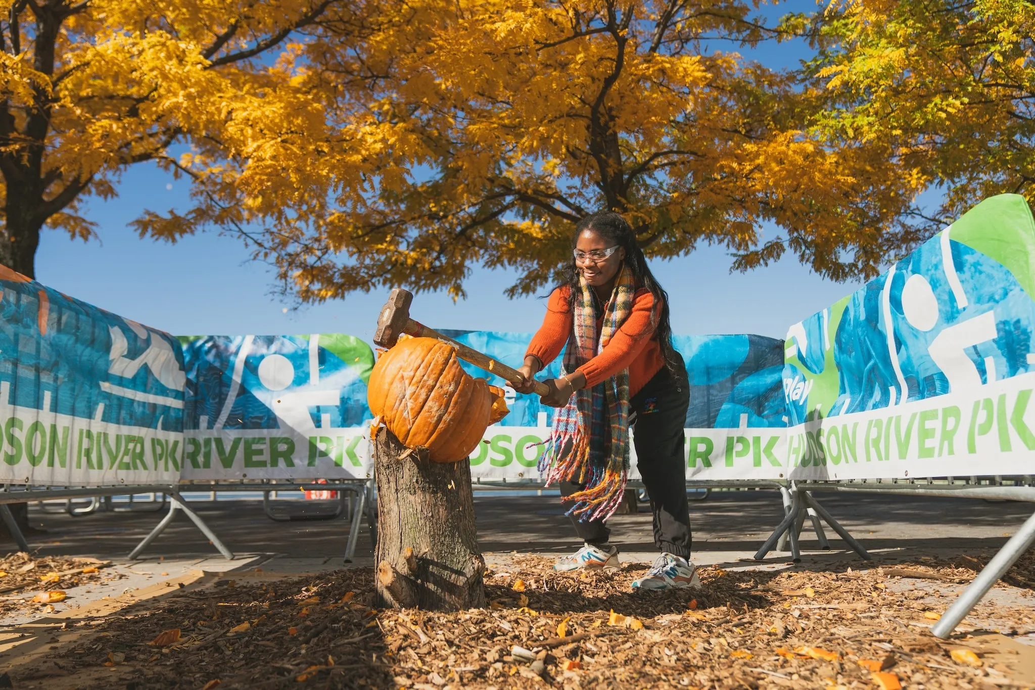 A woman smashing a pumpkin with a hammer