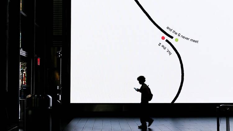 A person in silhouette walks by a black-and-white design on a digital screen.
