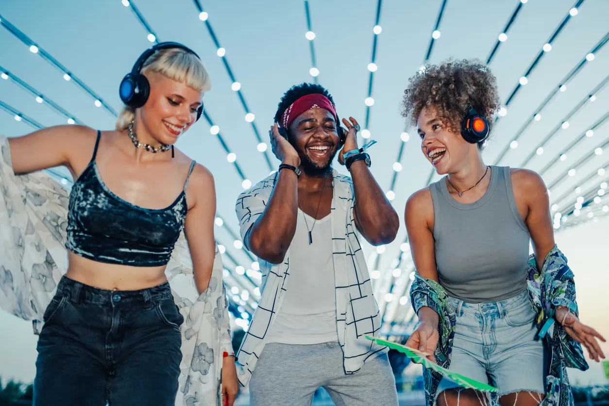 Three friends are dancing and having fun at silent disco, wearing wireless headphones