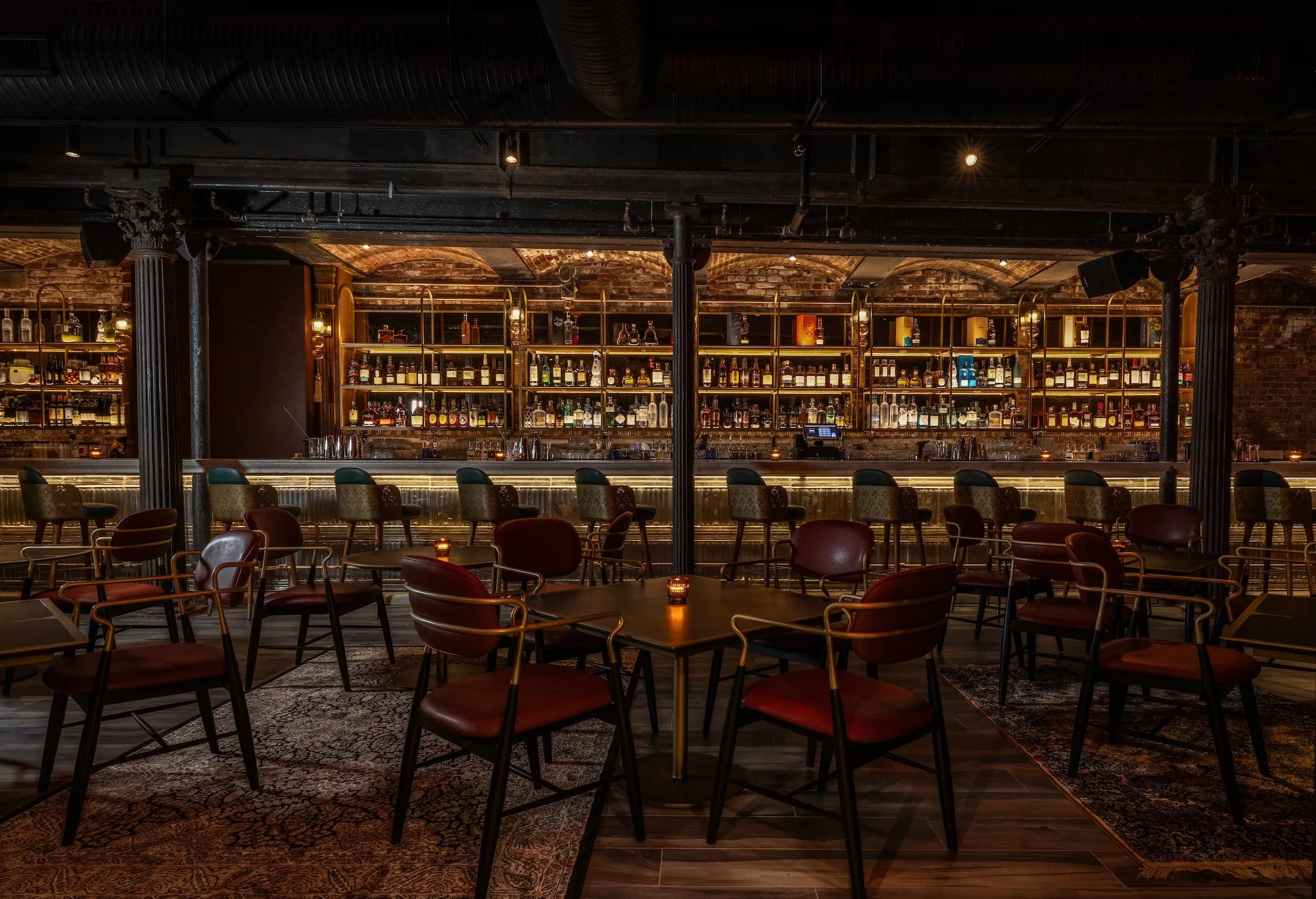 An illuminated bar with wooden tables and chairs