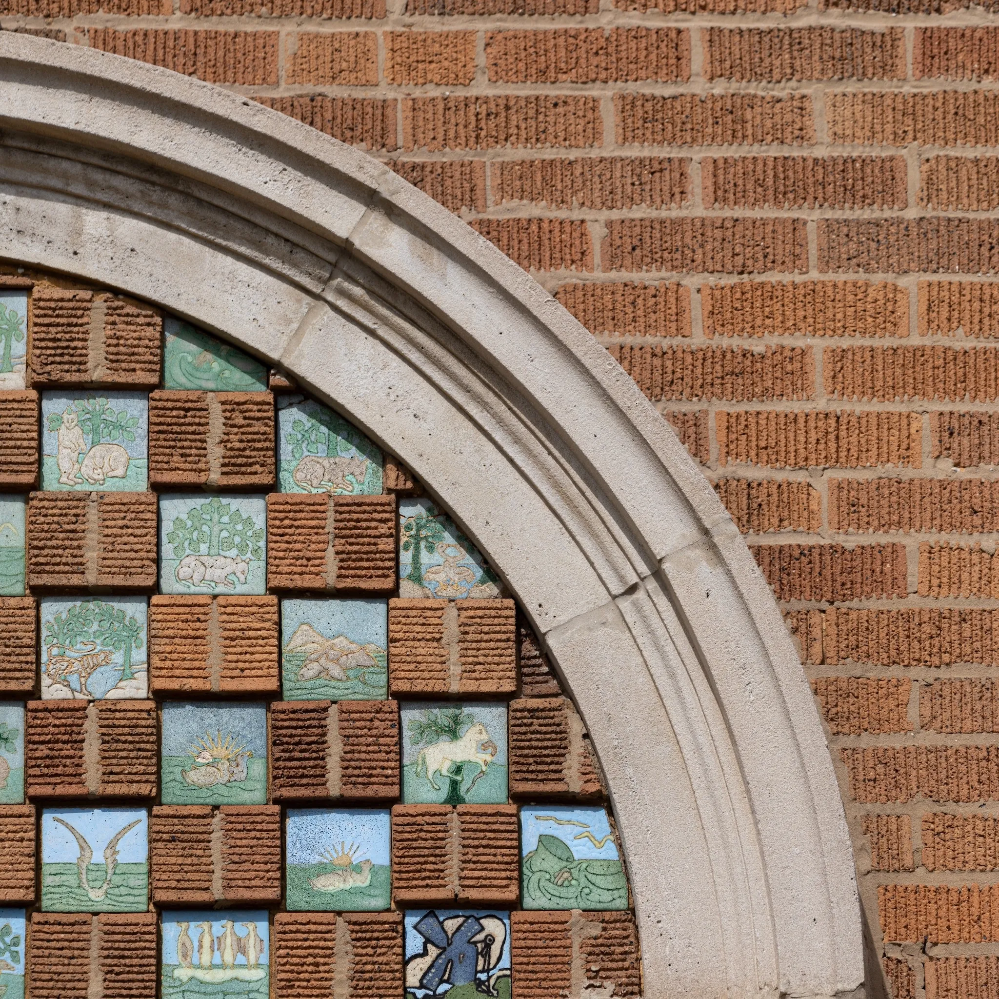 Small terra cotta tiles sit side-by-side with brick for a decorative checkerboard above the entrance to a brick home.