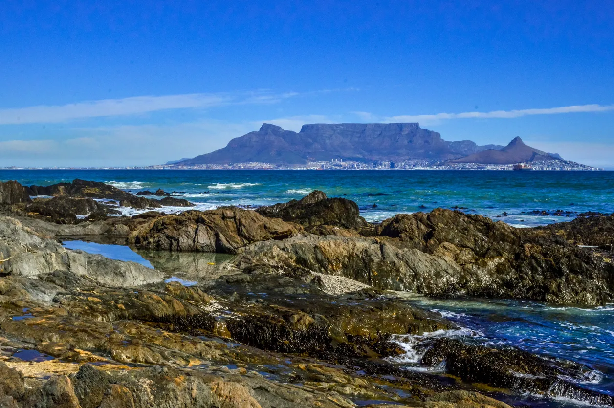 Table mountain with rocks and Atlantic ocean in foreground in cape town