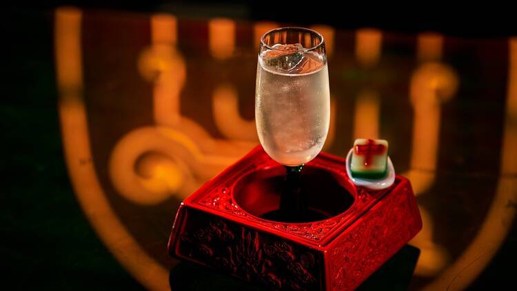 A clarified Long Island Iced tean with a small mahjong gummy next to it